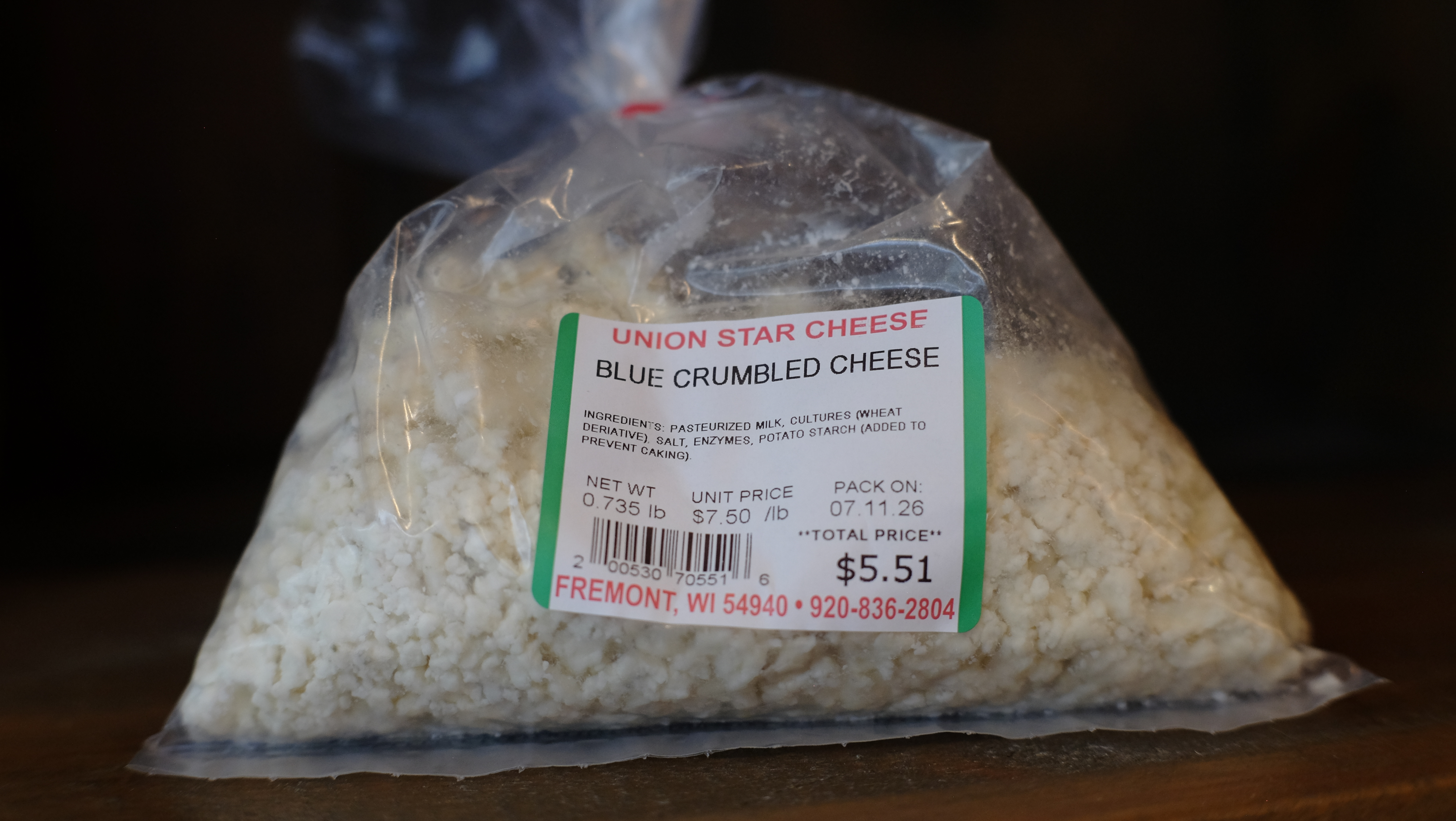 Bowl of blue cheese crumbles on a wooden surface